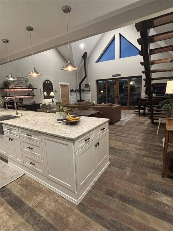 1794 County Road 4309 N, Greenville, TX 75401 Kitchen island with stone countertop, wood-finish flooring, industrial-style pendant lighting, soaring vaulted ceilings with triangular windows, and open-riser staircase