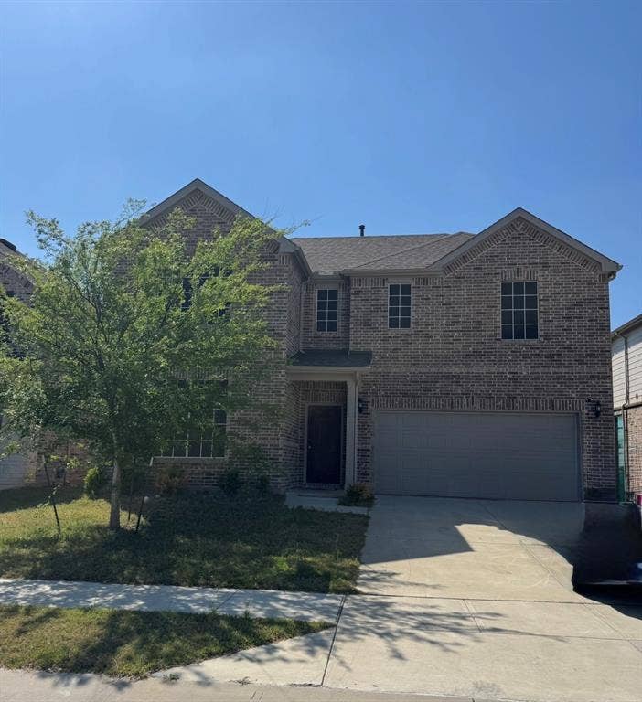 Home two-story brick exterior featuring a covered entry, multiple windows with grids, an attached two-car garage, and a concrete driveway