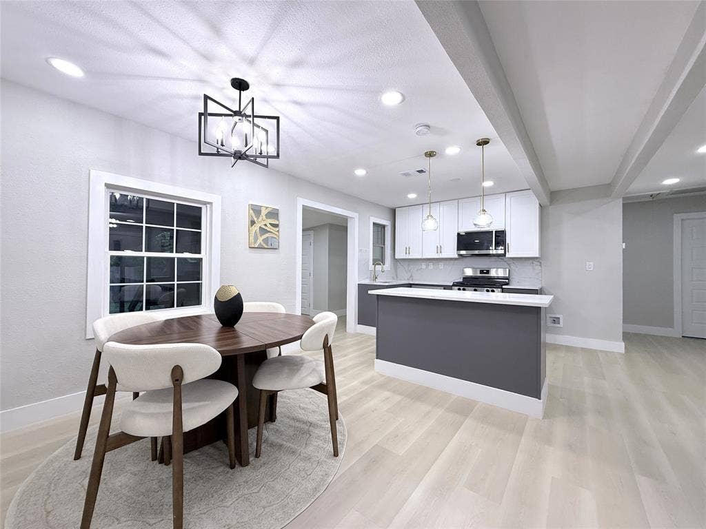 4522 Idaho Avenue, Dallas, TX 75216 Kitchen featuring white upper cabinetry, dark base cabinetry, a breakfast bar, recessed lighting, and wood-finish flooring