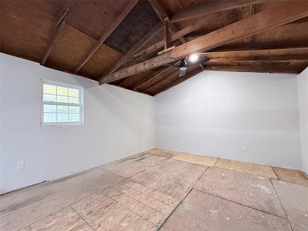 4522 Idaho Avenue, Dallas, TX 75216 Interior space featuring exposed wood-beam vaulted ceilings, paneled walls, a single-pane window, and an attached ceiling fan