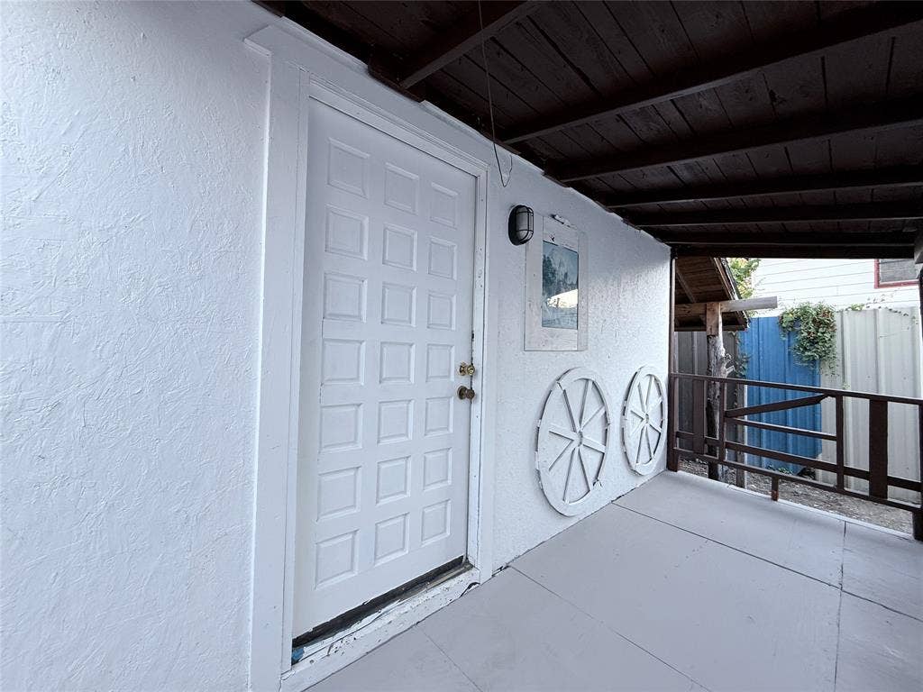 4522 Idaho Avenue, Dallas, TX 75216 Covered porch featuring a textured stucco exterior, wood-plank ceiling, solid-panel entry door, and perimeter railing