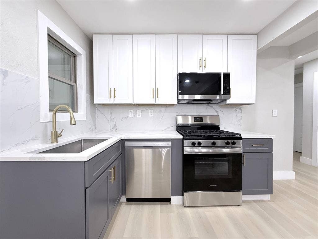 4522 Idaho Avenue, Dallas, TX 75216 Kitchen featuring two-tone shaker cabinetry, stone-patterned backsplash, stainless steel appliances, and a gold-finish arched faucet