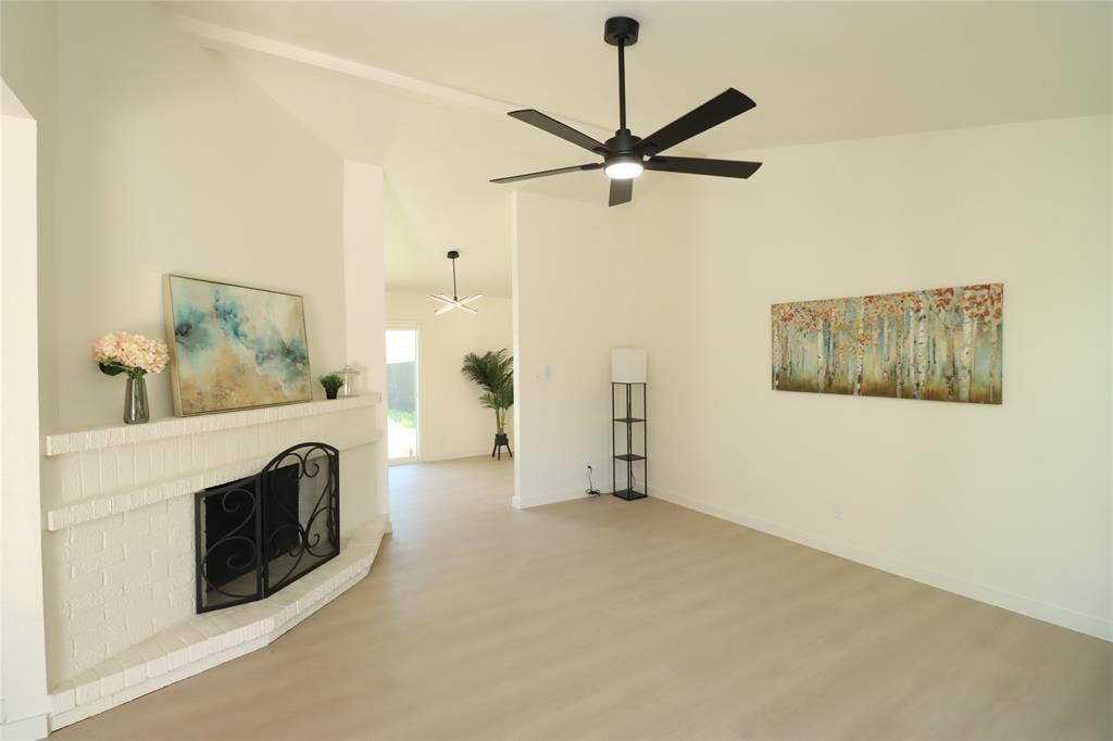 1518 Burgundy Street, Garland, TX 75040 Vaulted ceilings, luxurious high end vinyl plank throughout, masonry fireplace with a raised hearth, and modern ceiling fans