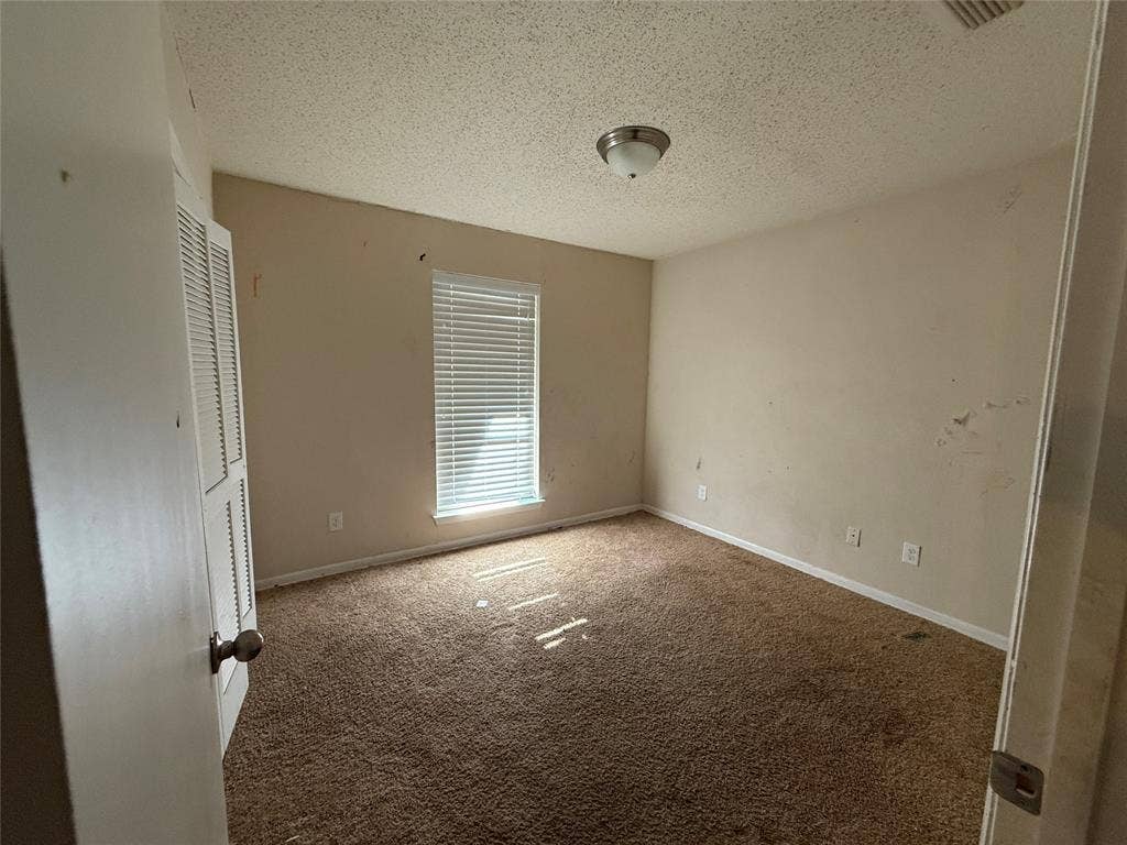 3825 Eugene Court N, Irving, TX 75062 Room featuring carpeted flooring, a single window with horizontal blinds, and a built-in closet with louvered doors