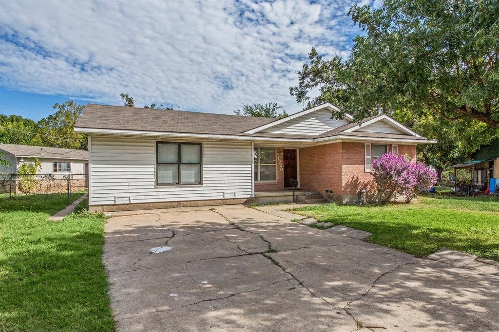 1220 Colfax Circle, Richardson, TX 75080 Exterior facade featuring a combination of brick and horizontal siding, an asphalt shingle roof, and a concrete driveway