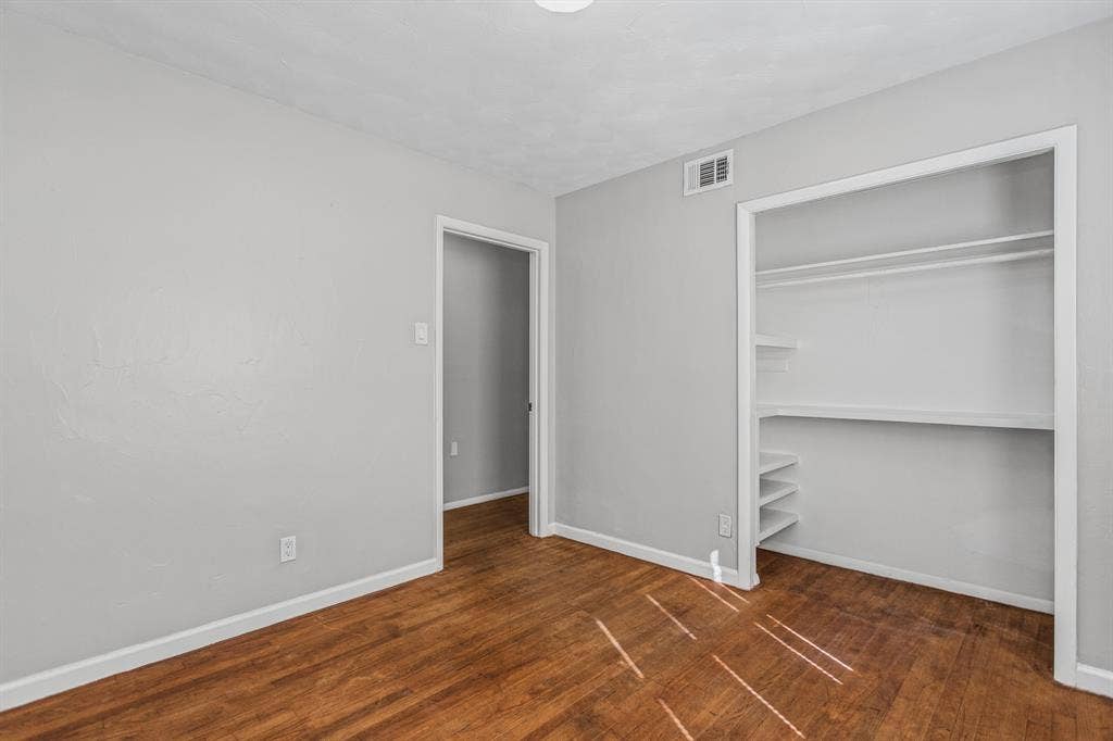 1220 Colfax Circle, Richardson, TX 75080 Room featuring wood-finish flooring, neutral wall paint, and a built-in closet with integrated shelving