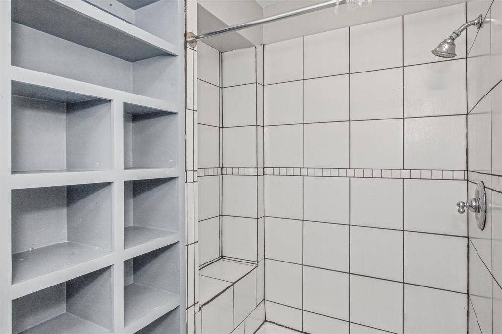 1220 Colfax Circle, Richardson, TX 75080 Built-in floor-to-ceiling shelving, tiled walk-in shower with integrated bench seat, and chrome plumbing fixtures