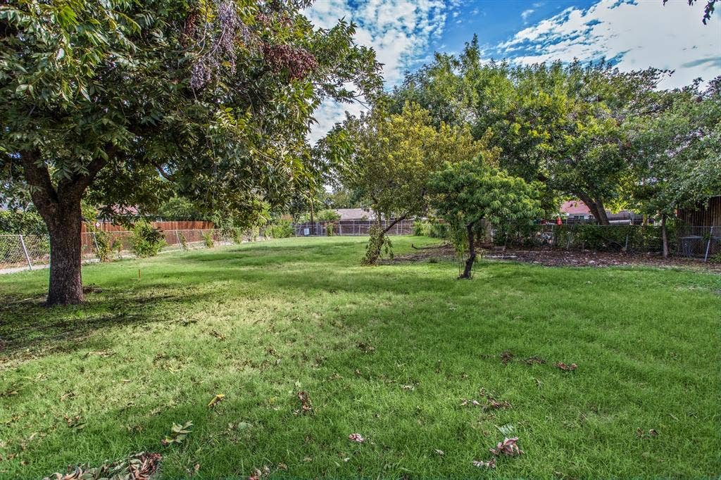 1220 Colfax Circle, Richardson, TX 75080 Expansive backyard featuring a manicured lawn, perimeter fencing, and mature trees