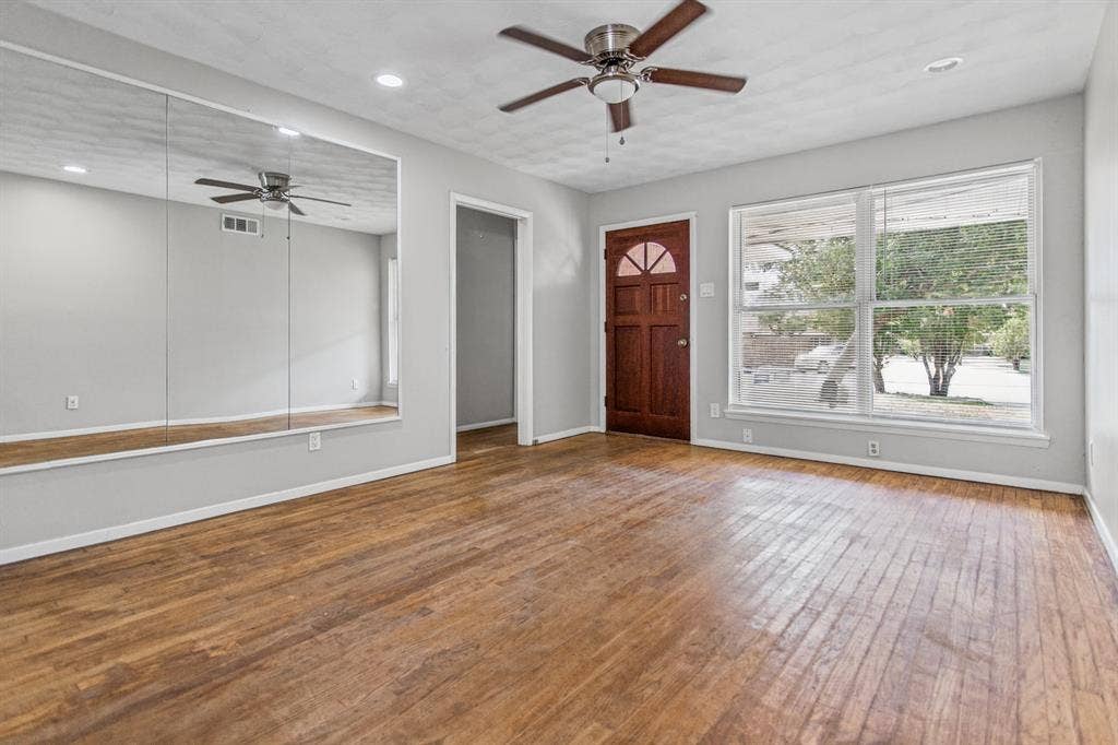 1220 Colfax Circle, Richardson, TX 75080 Wood-finish flooring, large wall-mounted mirrors, recessed lighting, ceiling fan with light fixture, and solid wood exterior door with arched glass panel