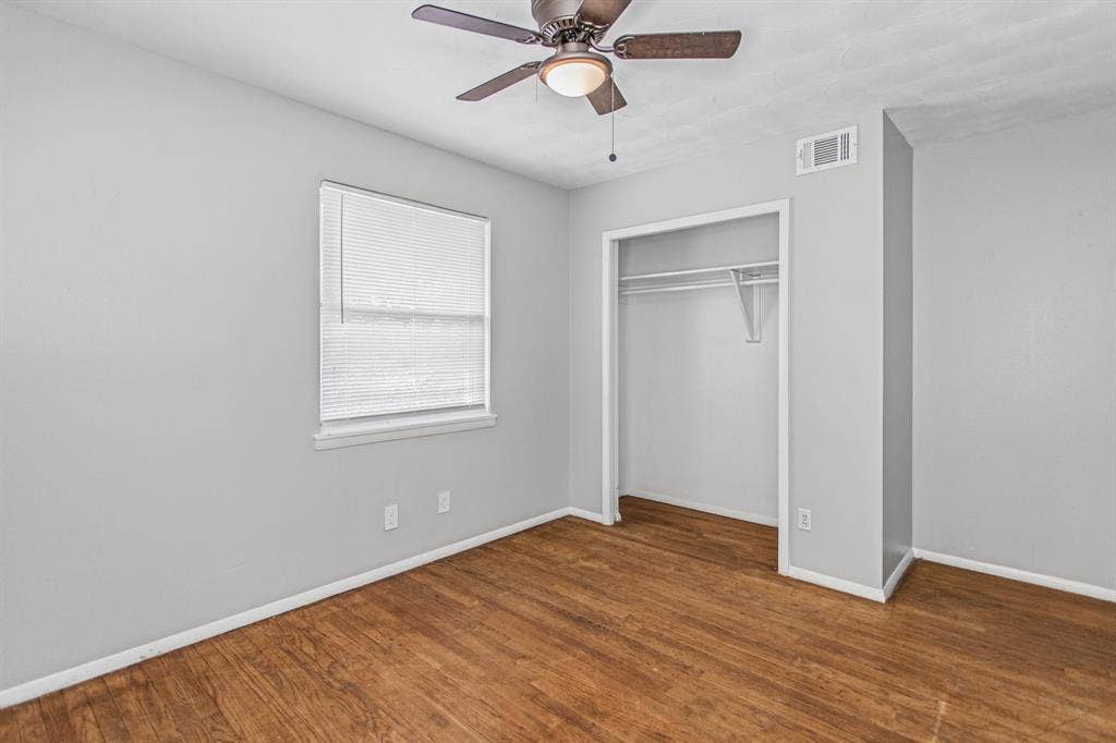 1220 Colfax Circle, Richardson, TX 75080 Room interior featuring wood-finish flooring, neutral wall paint, a ceiling fan with integrated lighting, and a closet with built-in shelving