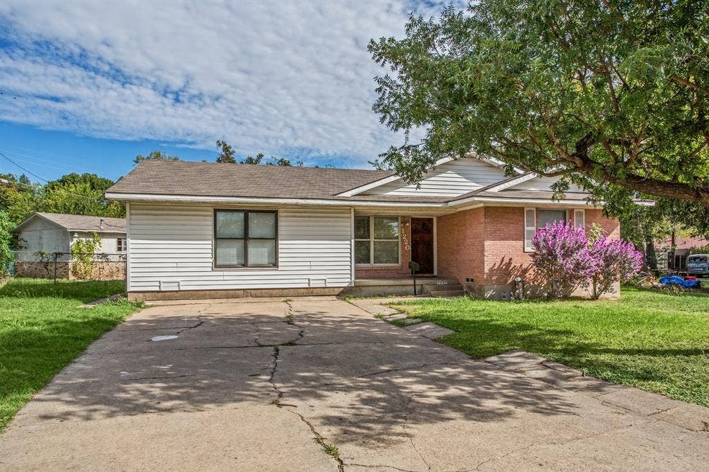 1220 Colfax Circle, Richardson, TX 75080 Single-story exterior featuring a brick and horizontal siding facade, asphalt shingle roof, concrete driveway, and mature landscaping