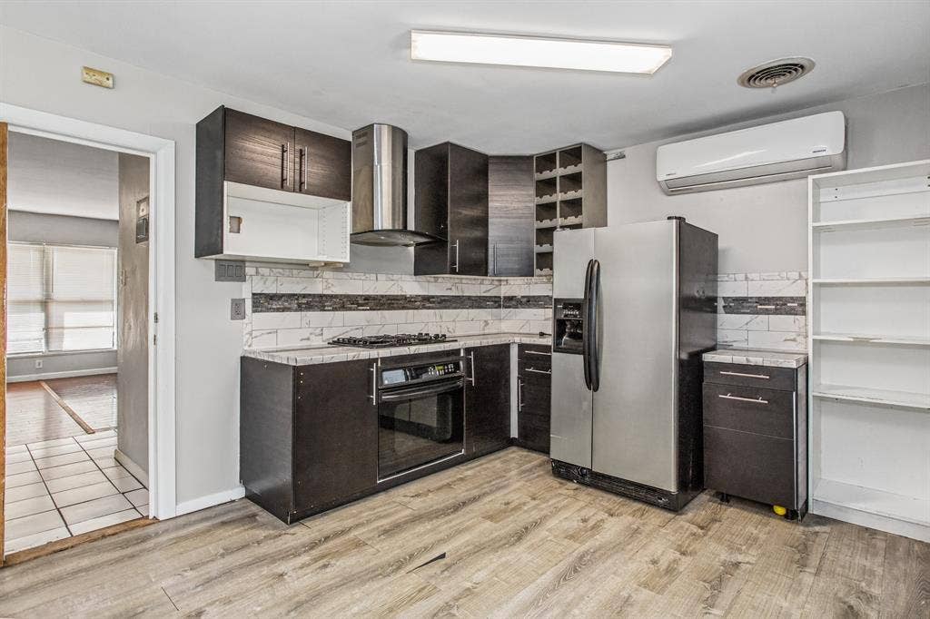 1220 Colfax Circle, Richardson, TX 75080 Kitchen featuring dark wood-finish cabinetry, stainless steel appliances, a tile backsplash, wood-finish flooring, and a built-in wine rack