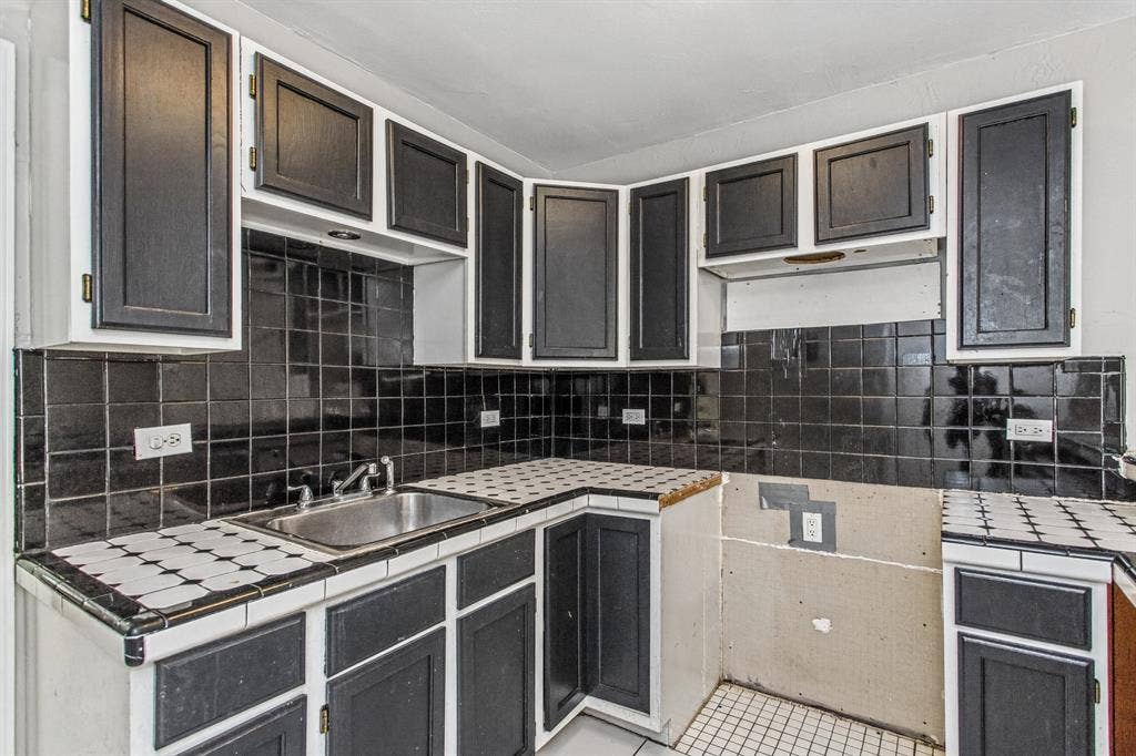 1220 Colfax Circle, Richardson, TX 75080 Kitchen featuring dark-finish shaker cabinetry, patterned tile countertops, black tiled backsplash, and a stainless steel undermount sink