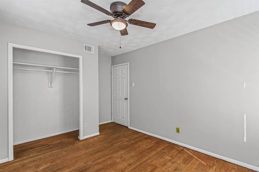 1220 Colfax Circle, Richardson, TX 75080 Room featuring wood-finish flooring, a ceiling fan with integrated lighting, and a closet with a built-in shelf and rod