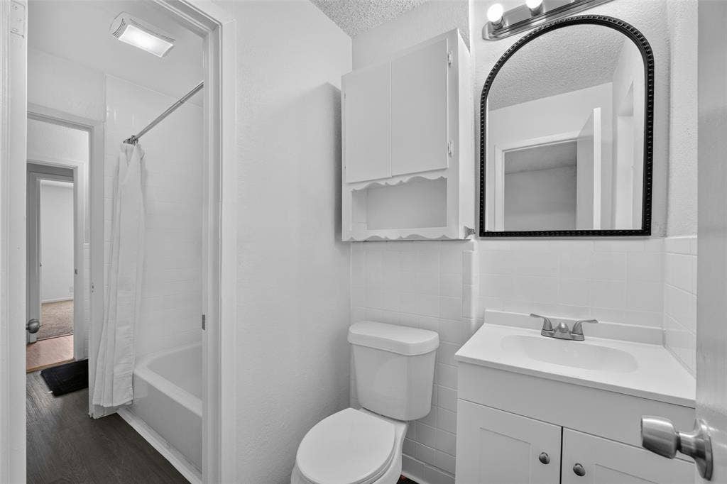 3532 Hilton Drive, Mesquite, TX 75150 Bathroom featuring a vanity with integrated sink, arched wall mirror, wall-mounted storage cabinet, and a shower-tub combination with tile surround