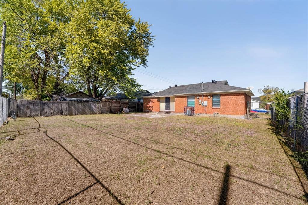 3532 Hilton Drive, Mesquite, TX 75150 Expansive backyard featuring a brick exterior, wood privacy fencing, mature trees, and a ground-level concrete patio