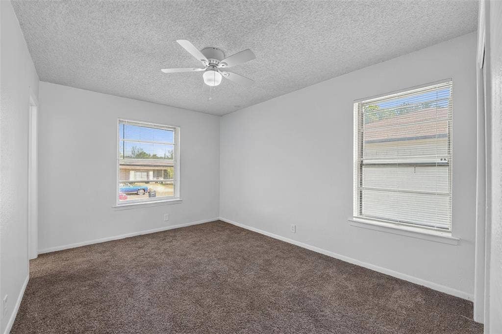 3532 Hilton Drive, Mesquite, TX 75150 Room interior featuring wall-to-wall carpeting, two dual-pane windows with horizontal blinds, and a central ceiling fan with integrated lighting