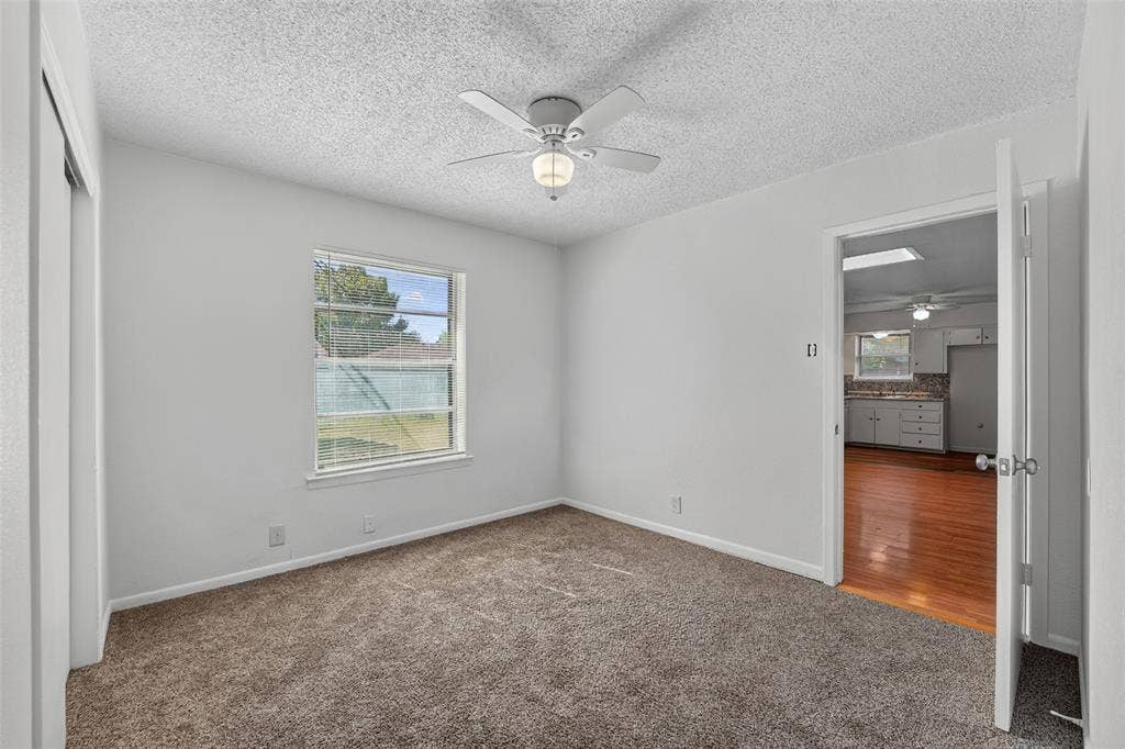 3532 Hilton Drive, Mesquite, TX 75150 Interior room featuring neutral carpeting, a ceiling-mounted fan with integrated light fixture, a single-pane window, and a sliding closet door