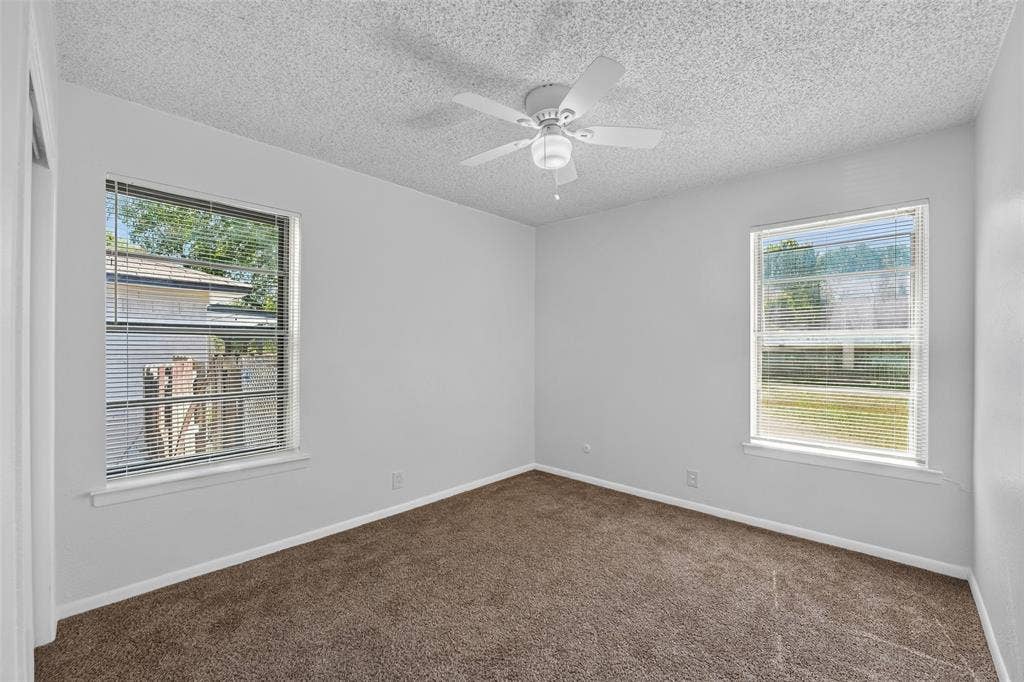 3532 Hilton Drive, Mesquite, TX 75150 Neutral wall-to-wall carpeting, two dual-pane windows with horizontal blinds, and a white ceiling-mounted fan with light fixture