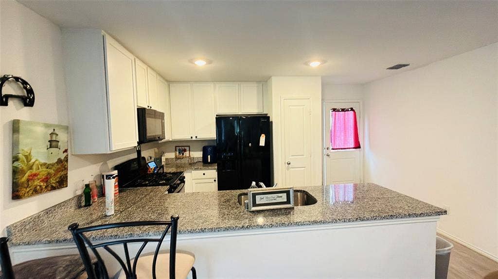 Kitchen featuring white cabinetry, stone-surface countertops, integrated breakfast bar, and recessed lighting