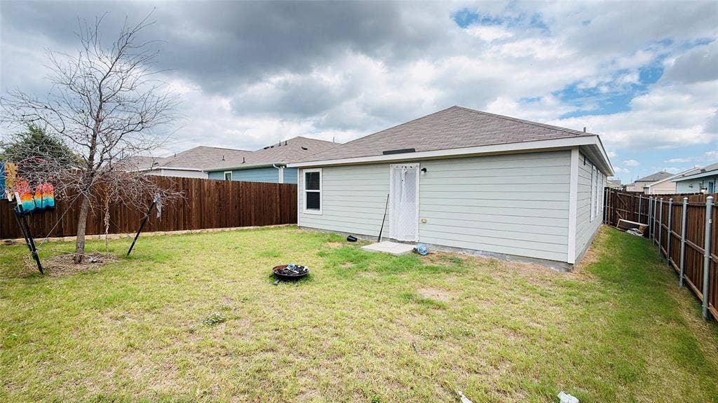 Rear yard featuring horizontal siding, a gabled roof, and wood-panel privacy fencing