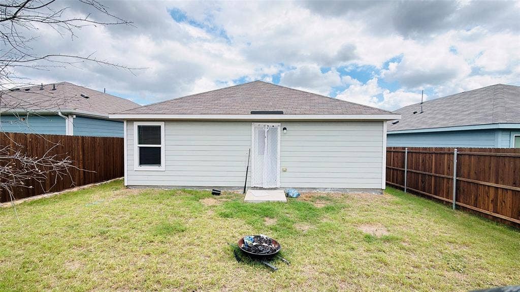 Rear exterior featuring horizontal lap siding, a hipped roof, and a fully fenced backyard