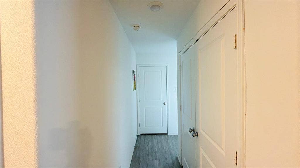 Hallway featuring wood-finish flooring, two-panel interior doors, and recessed ceiling lighting