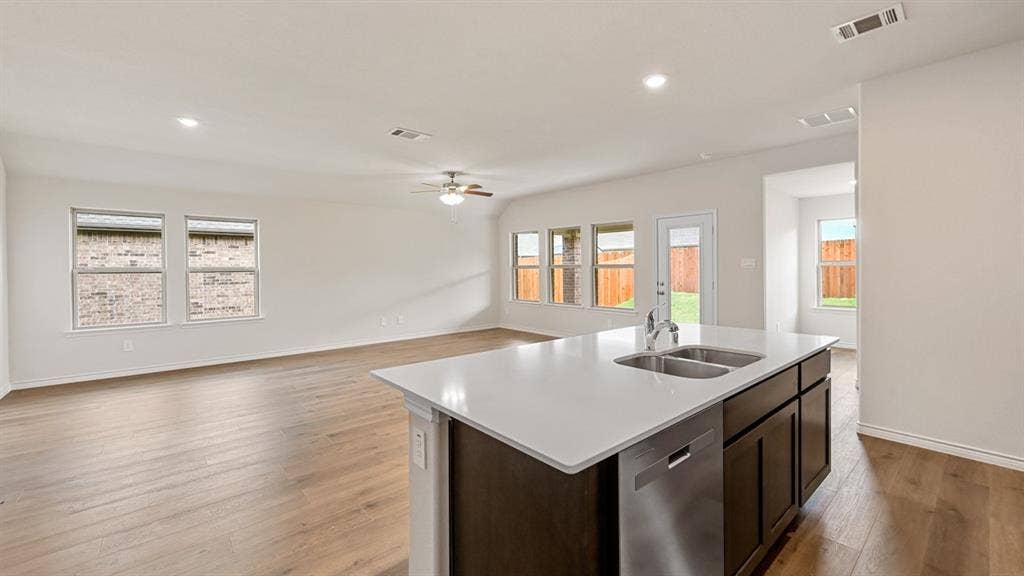 Spacious open-concept living area with wood-finish flooring, recessed lighting, and a ceiling fan