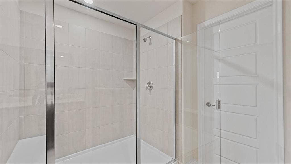 Glass-enclosed shower with a built-in niche, tiled walls, and a chrome shower fixture