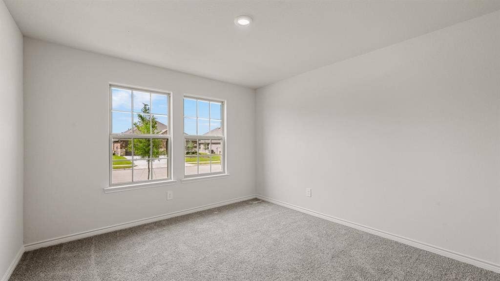 Bright interior space featuring two large windows, recessed ceiling lighting, and grey carpeting
