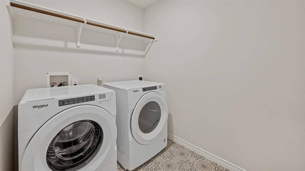 Dedicated laundry area with patterned floor tiles, overhead shelving, and a garment rod