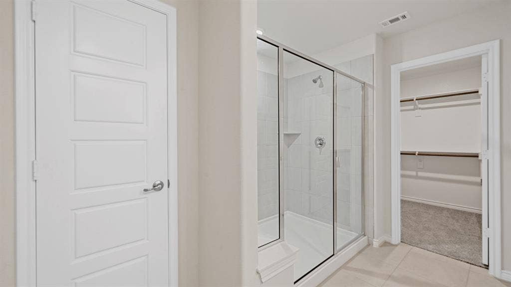 Shower with a glass enclosure, tiled walls, and a built-in shelf
