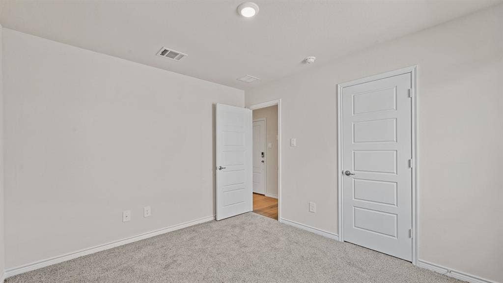 Light gray wall color, textured carpeting, recessed lighting, and a paneled interior door