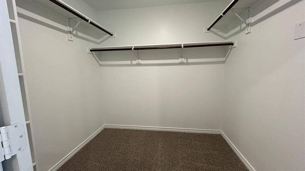 410 Campfield Drive, Caddo Mills, TX 75135 Walk-in closet featuring neutral carpeting and built-in shelving with multiple hanging rods