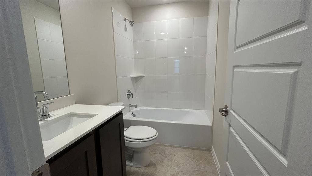410 Campfield Drive, Caddo Mills, TX 75135 Bathroom featuring a vanity with a white countertop and rectangular undermount sink, dark-finish cabinetry, a white tub-and-shower combination with tiled surround, and tile flooring