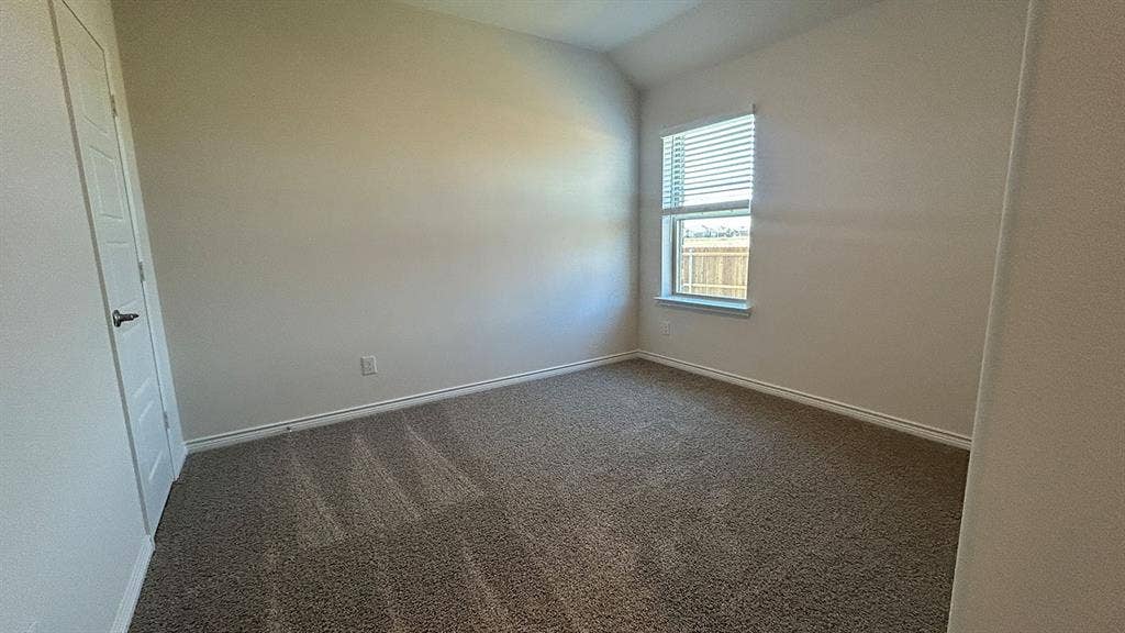 410 Campfield Drive, Caddo Mills, TX 75135 Interior room featuring neutral-toned carpeting, vaulted ceilings, and a single window with fitted blinds