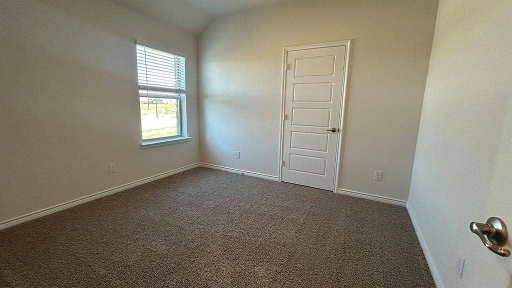 410 Campfield Drive, Caddo Mills, TX 75135 Neutral interior featuring high-vaulted ceilings, neutral carpeting, a single-hung window with horizontal blinds, and a five-panel interior door with satin-finish hardware