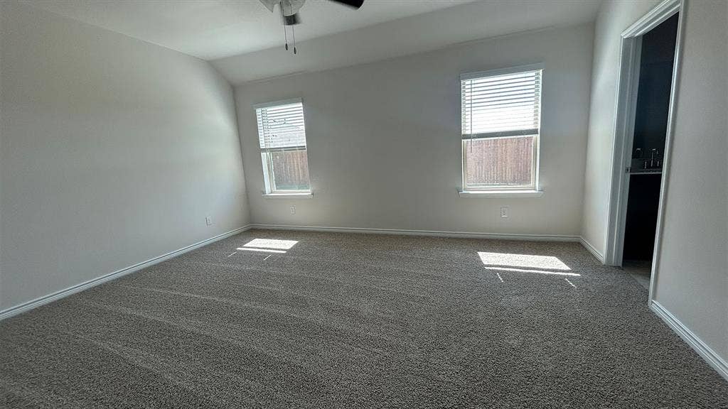 410 Campfield Drive, Caddo Mills, TX 75135 Bedroom featuring neutral wall-to-wall carpeting, vaulted ceilings, a ceiling fan, and two windows with horizontal blinds