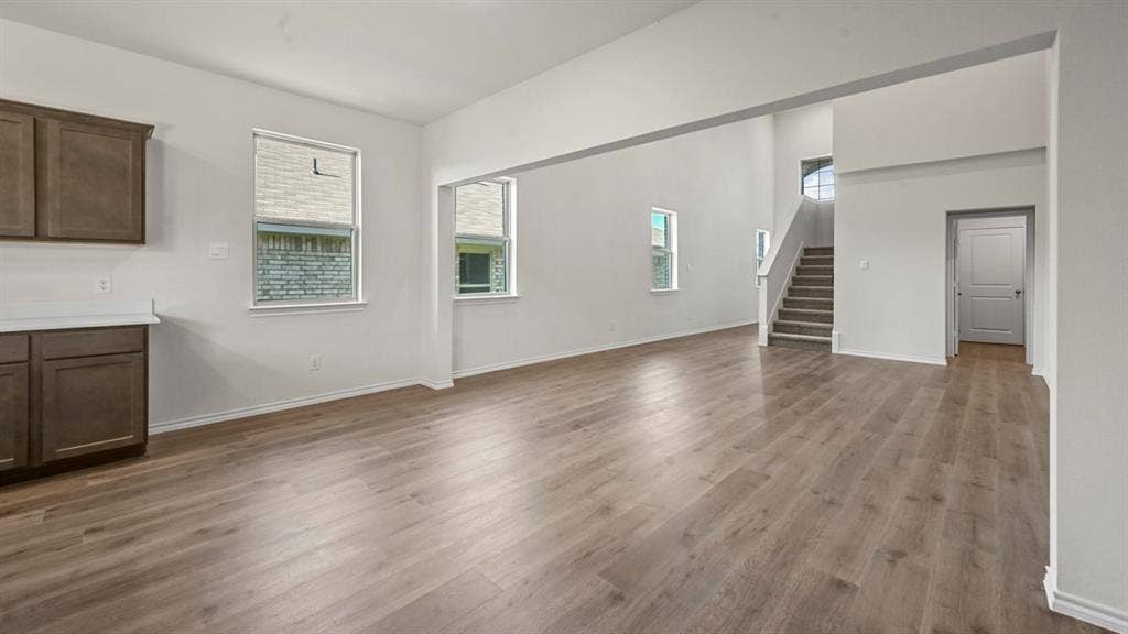 5727 Sunshine Lane, Crandall, TX 75114 Spacious open-concept interior with wood-finish flooring, white walls, and abundant natural light from multiple windows