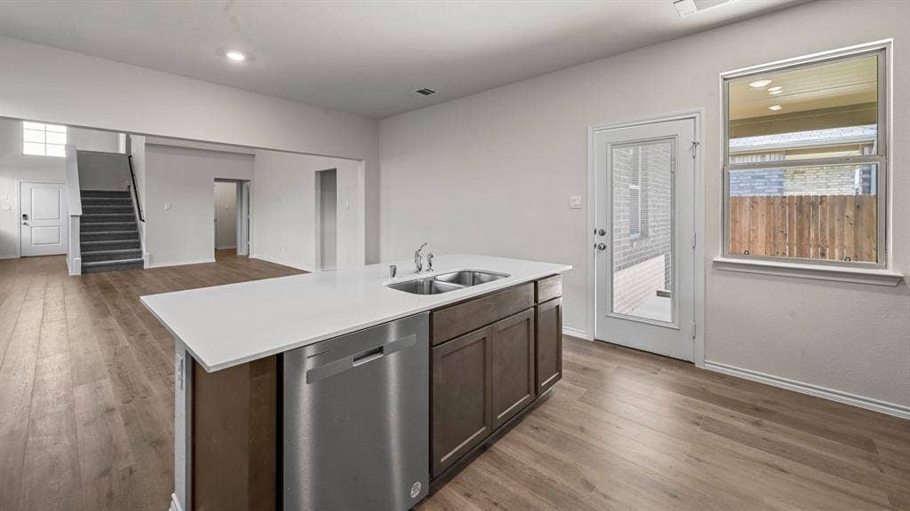 5727 Sunshine Lane, Crandall, TX 75114 Kitchen island featuring an undermount double sink, stainless steel dishwasher, and a light-toned countertop
