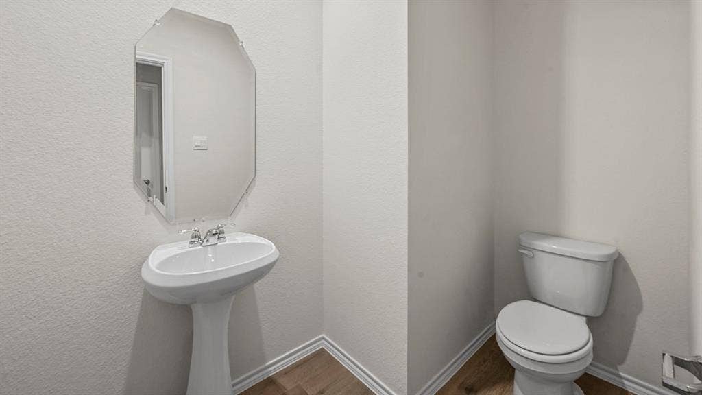 5727 Sunshine Lane, Crandall, TX 75114 Pedestal sink with chrome faucet, octagonal mirror, toilet, and wood-finish flooring