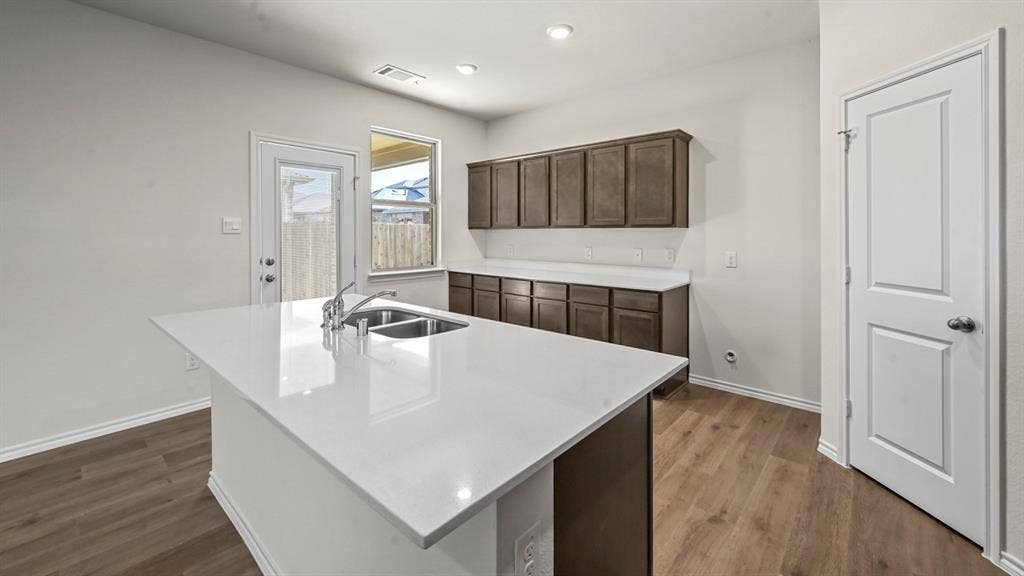 5727 Sunshine Lane, Crandall, TX 75114 Kitchen island with a double basin sink and chrome faucet, wood-finish flooring, white countertops, and dark wood-finish cabinetry