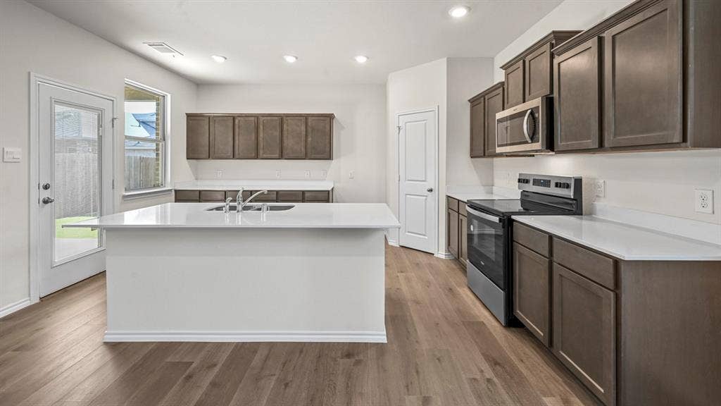 5727 Sunshine Lane, Crandall, TX 75114 Kitchen featuring a central island with an integrated sink, wood-finish flooring, stainless steel appliances, white countertops, and recessed lighting