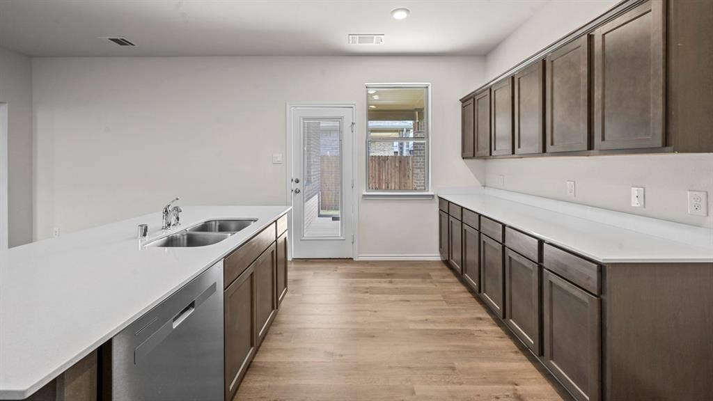 5727 Sunshine Lane, Crandall, TX 75114 Modern kitchen with extensive dark wood-finish cabinetry, light-toned countertops, a stainless-steel dishwasher, and wood-finish flooring