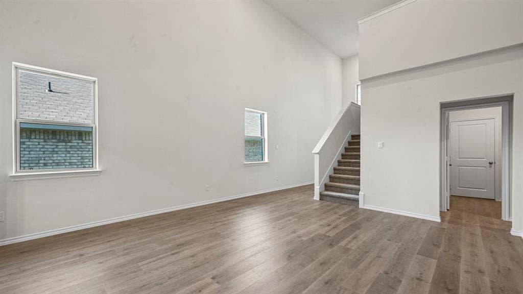 5727 Sunshine Lane, Crandall, TX 75114 High vaulted ceilings, wood-finish flooring, two large windows, a carpeted staircase, and a paneled interior door