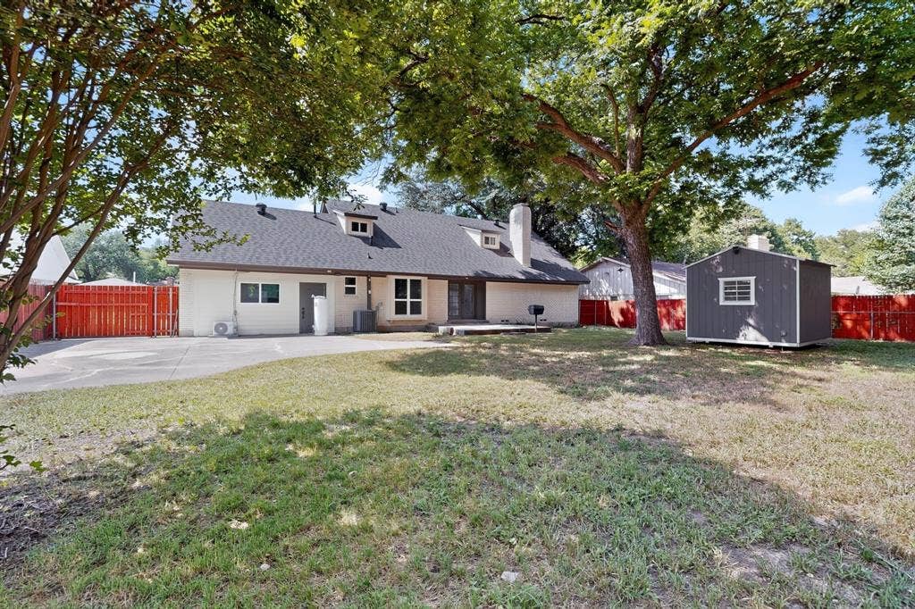550 Glen Oaks Boulevard, Dallas, TX 75232 Expansive backyard featuring a concrete patio, mature trees, a detached storage shed, and perimeter privacy fencing
