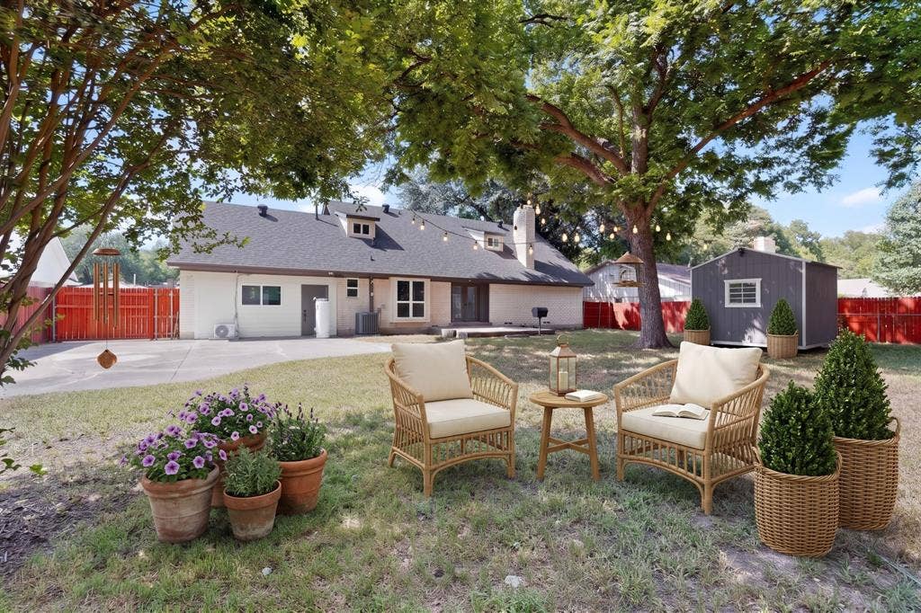 550 Glen Oaks Boulevard, Dallas, TX 75232 Expansive backyard featuring a concrete patio, mature shade trees, a detached storage structure, and perimeter fencing