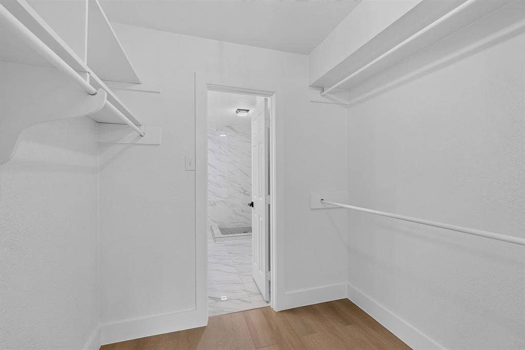 550 Glen Oaks Boulevard, Dallas, TX 75232 Walk-in closet featuring white built-in shelving, hanging rods, and wood-finish flooring