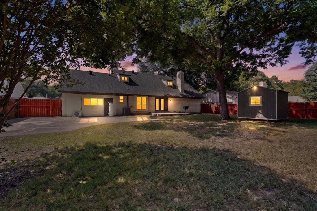 550 Glen Oaks Boulevard, Dallas, TX 75232 Spacious backyard featuring mature trees, a concrete patio, a detached storage shed, and perimeter wood fencing