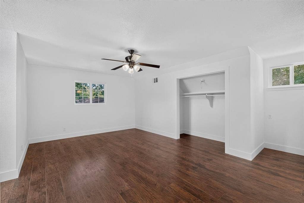 550 Glen Oaks Boulevard, Dallas, TX 75232 Spacious room featuring wood-finish flooring, recessed closet with built-in shelving, multi-pane windows, and a ceiling fan with integrated lighting